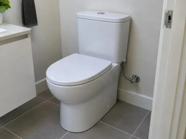 New white toilet in a tiled bathroom beside a vanity and wall in Cooks Hill